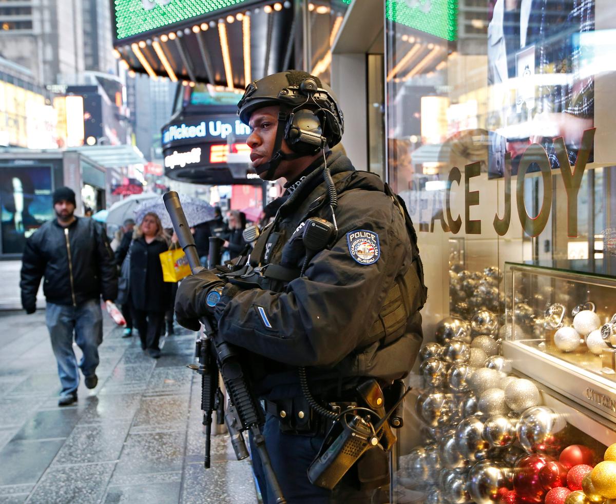 A heavily armed counterterrorism officer takes shelter beneath an overhang above a store in Times Square, on Dec. 29, 2016. (AP Photo/Kathy Willens)
