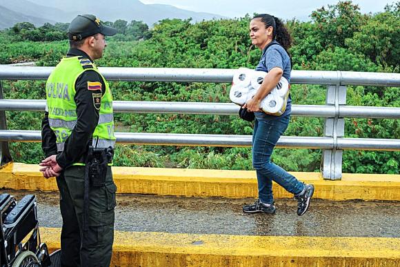 A woman crosses a bridge connecting Venezuela and Colombia after buying essential goods, such as toilet paper, in Colombia due to shortages in Venezuela, on July 16. (GEORGE CASTELLANOS/AFP/Getty Images)