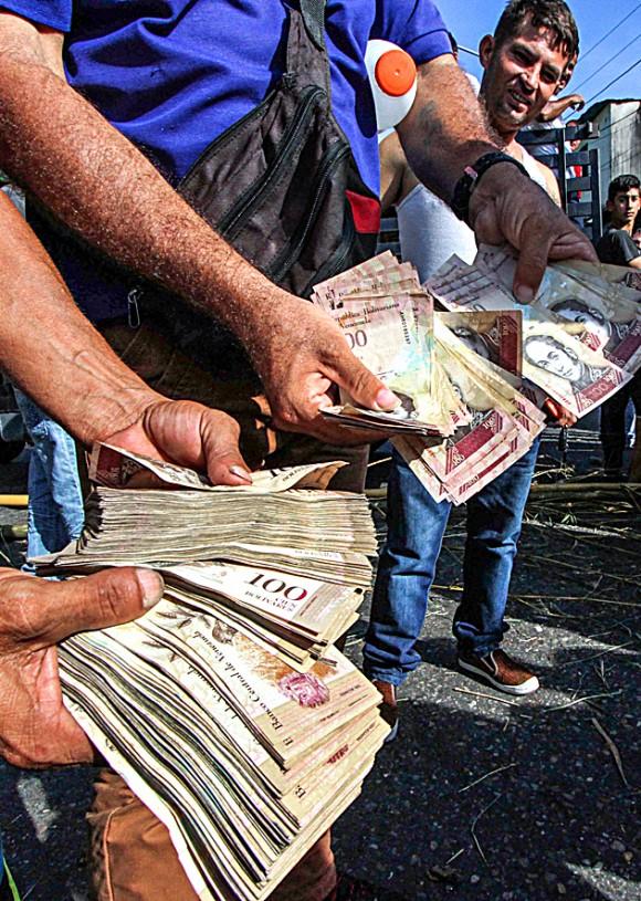 People hold up 100-bolivar notes—each worth only $0.04—during a protest over a lack of cash in San Cristóbal, Venezuela, on Dec. 16. (GEORGE CASTELLANOS/AFP/Getty Images)