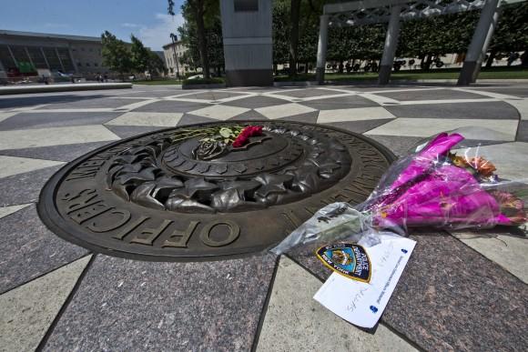 In this file photo, five red roses on the bronze medallion with another bouquet of flowers and a note in support of the Dallas Police Department are seen at The National Law Enforcement Officers Memorial in Washington. (AP Photo/Alex Brandon)