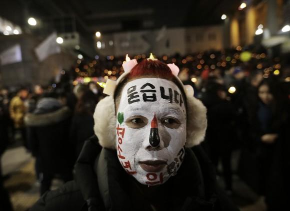 A protester with his face painted attends a candle light vigil calling for impeached President Park Geun-hye to step down in Seoul, South Korea, on Dec. 31, 2016. (AP Photo/Ahn Young-joon)