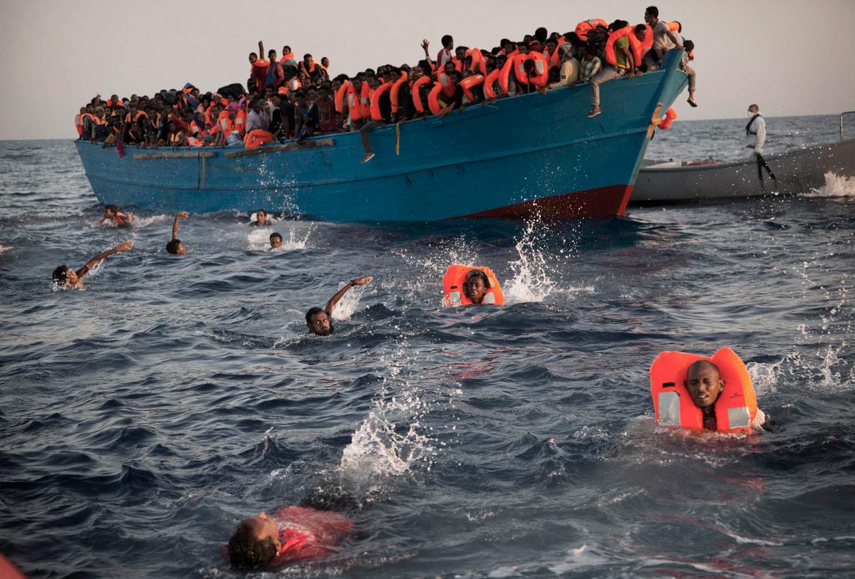 Migrants, most from Eritrea, jump into the water from a crowded wooden boat as they are helped by members of an NGO during a rescue operation in the Mediterranean sea near Libya on Aug. 29. (AP Photo/Emilio Morenatti)