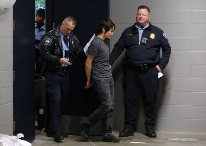 A Minneapolis police officer escorts a protester from U.S. Bank Stadium after an NFL football game between the Minnesota Vikings and the Chicago Bears Sunday, Jan. 1, 2017, in Minneapolis. Protesters against the Dakota Access Pipeline rappelled from the catwalk during the game. (AP Photo/Andy Clayton-King)