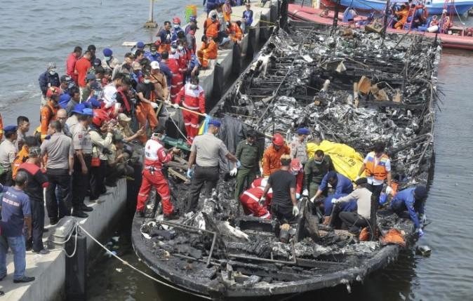 Rescuers search for victims from the wreckage of a ferry that caught fire off the coast of Jakarta after it was docked at Muara Angke Port in Jakarta, Indonesia, Sunday, Jan. 1, 2017. The vessel was carrying more than 230 people from the port to Tidung, a resort island in the Kepulauan Seribu chain, when it caught fire, officials said. (AP Photo/Rhana Ananda)
