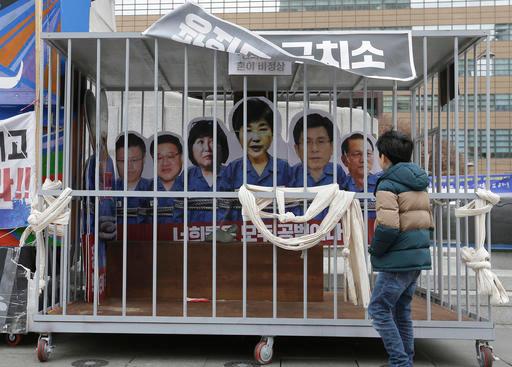 A boy looks at portraits of impeached South Korea's President Park Geun-hye, center, and her aides in a mock jail cell in Seoul, South Korea, on Jan. 5, 2017. (AP Photo/Ahn Young-joon)