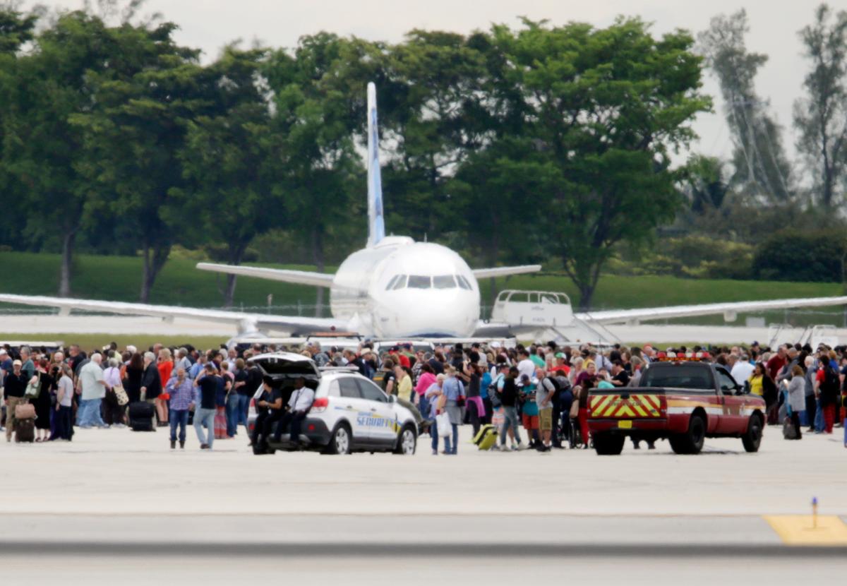 People stand on the tarmac at the Fort Lauderdale-Hollywood International Airport after a shooter opened fire inside a terminal of the airport, killing several people and wounding others before being taken into custody in Fort Lauderdale, Fla., on Jan. 6, 2017. (AP Photo/Lynne Sladky)