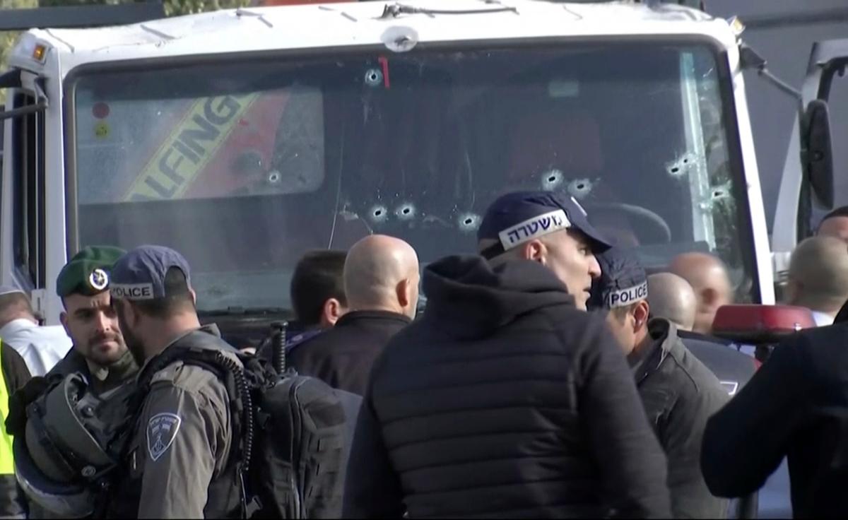 This frame grab from video, shows an Israeli emergency services personnel in front of the truck, with bullet holes in the windshield, that was used in an attack that killed at least four people and wounded several others, in Jerusalem on Jan. 8, 2017. (AP Photo)