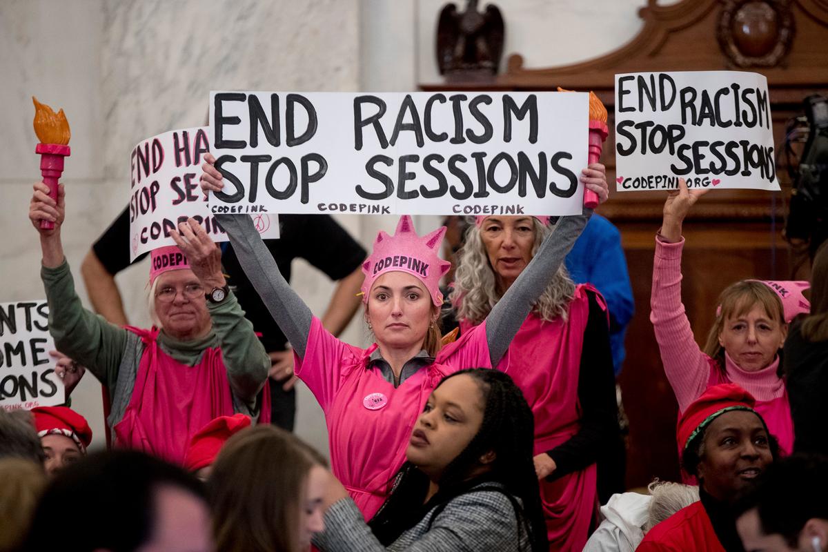 CodePink activists, including co-founder Medea Benjamin (R) hold up signs against Attorney General-designate, Sen. Jeff Sessions, R-Ala., on Capitol Hill in Washington on Jan. 10, 2017. (AP Photo/Andrew Harnik)
