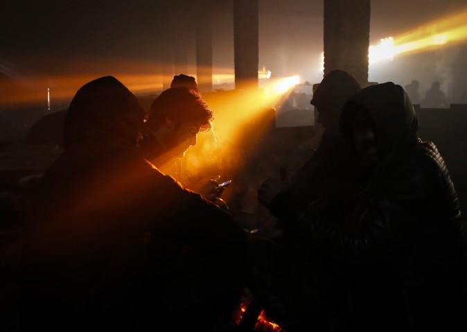 Migrants warm themselves by a fire inside a derelict customs warehouse on in Belgrade, Serbia, on Jan. 8. (Srdjan Stevanovic/Getty Images)