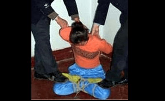 Torture reenactment: Tied with legs crossed (Minghui.org)