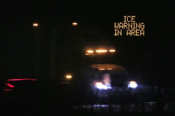 Traffic moves past an icing warning sign at night on I-70 west Lawrence, Kan., on Jan. 14, 2017. (AP Photo/Orlin Wagner)
