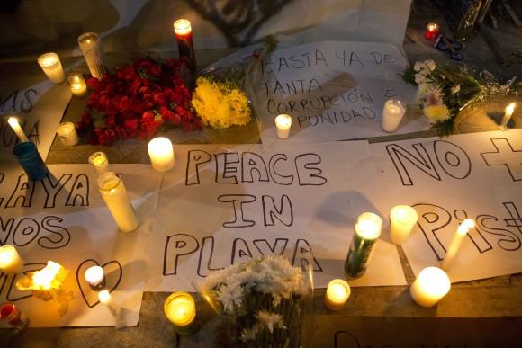 Candles sit atop banners proclaiming in Spanish "Peace in Playa," "No more pistols," and "Enough already of so much corruption and impunity," outside the Blue Parrot club, where several people were killed in early morning gunfire, in Playa del Carmen, Mexico, on Jan. 16, 2017. (AP Photo/Rebecca Blackwell)