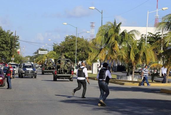 Police run near the state prosecutors' office after a gunmen opened fire on the building in Cancun, Mexico, on Jan. 17, 2017. (AP Photo)