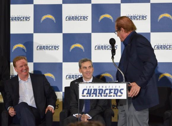 Chargers owner Dean Spanos (R) tells Rams COO Kevin Demoff that he hopes the two teams face off at the Superbowl, while NFL Commissioner Roger Goodell (L) laughs, at a rally in Inglewood, Calif. on Jan. 18. (Sarah Le/Epoch Times)