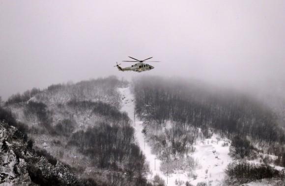 A Finance Police helicopter hovers above the town of Farindola, central Italy, Jan. 19, 2017. (AP Photo/Gregorio Borgia)