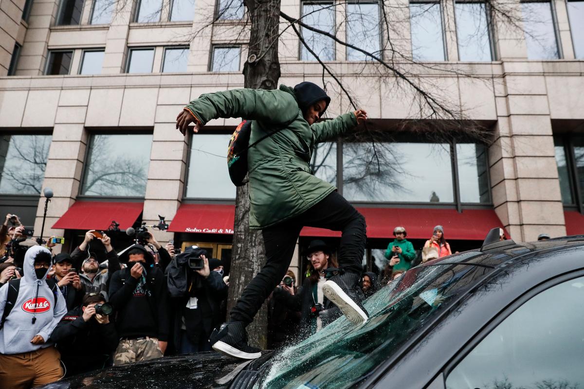A protestor kicks in a windshield during a demonstration in Washington on Jan. 20, 2017, after the inauguration of President Donald Trump. (AP Photo/John Minchillo)