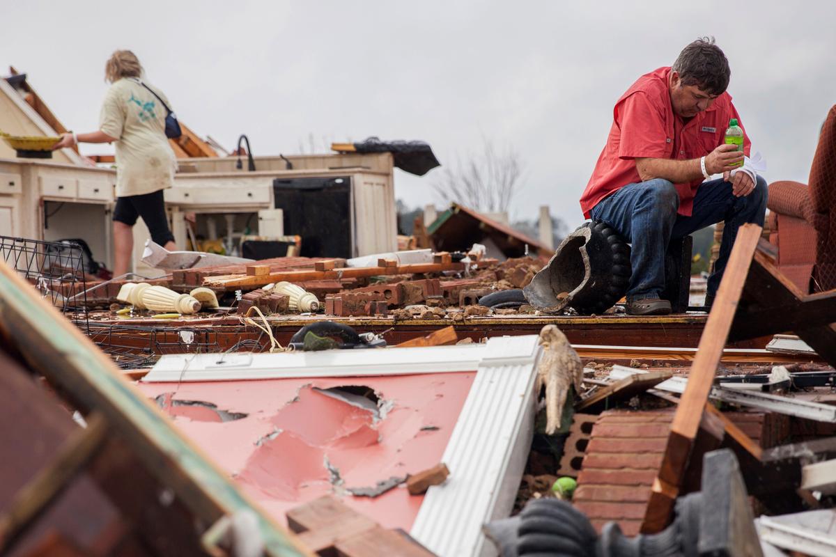 Jeff Bullard sits in what used to be the foyer of his home as his daughter, Jenny Bullard, looks through debris at their home that was damaged by a tornado in Adel, Ga., on Jan. 22, 2017. (AP Photo/Branden Camp)