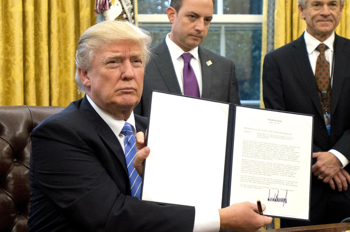President Donald Trump shows the Executive Order withdrawing the US from the Trans-Pacific Partnership after signing it in the Oval Office of the White House in Washington, DC on Jan. 23, 2017. (Ron Sachs - Pool/Getty Images)