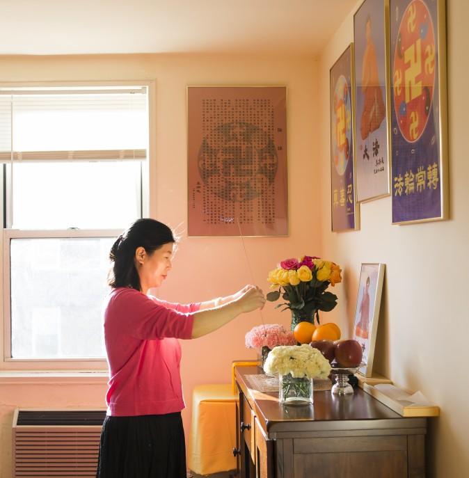 Wang Huijuan pays her respects to the founder of Falun Gong at her home in Queens, New York, on Jan. 8, 2016. With her husband and daughter, she escaped China in 2014 and was granted asylum after years of torture for practicing Falun Gong. (Samira Bouaou/Epoch Times)