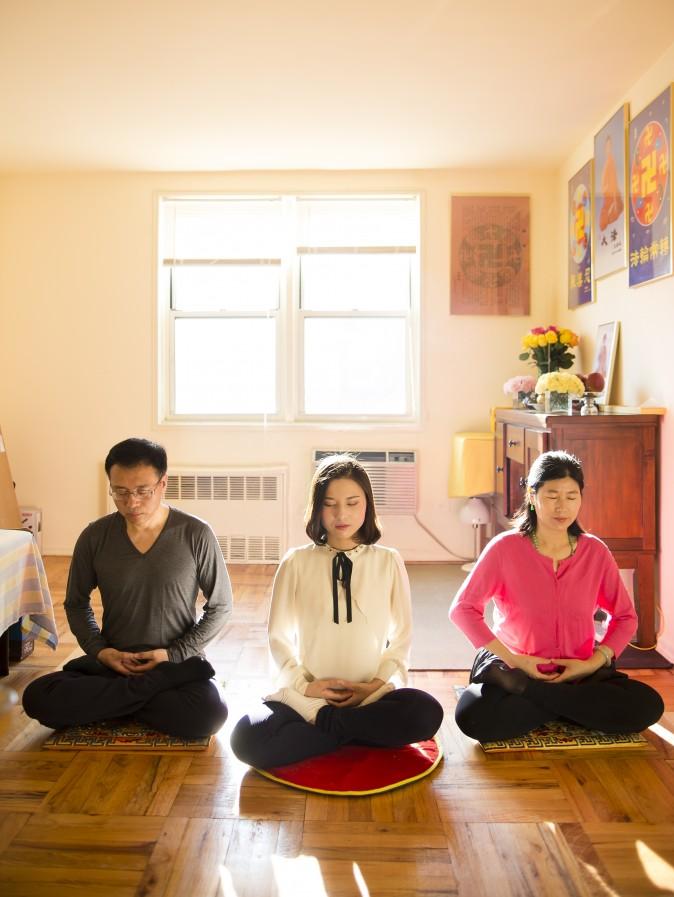 (L-R) Li Zhenjun, Li Fuyao, and Wang meditate at their home in Queens, New York. (Samira Bouaou/Epoch Times)
