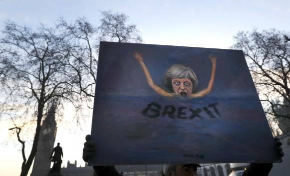 Artist Kaya Mar holds a painting near Parliament in London, Tuesday, Jan. 24, 2017. (AP Photo/Kirsty Wigglesworth)