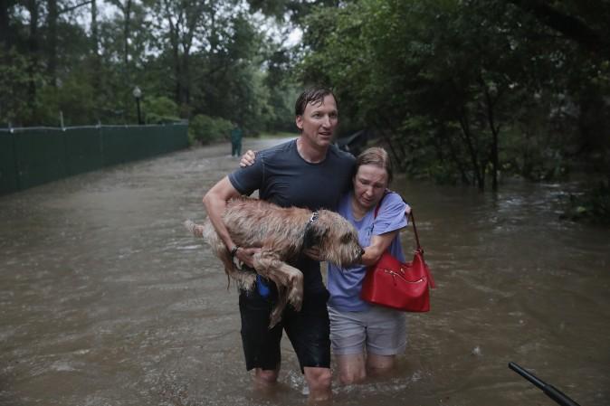 Andrew White (L) helps a neighbor down a street after rescuing her from her home in his boat in the upscale River Oaks neighborhood that was inundated with flooding from Hurricane Harvey in Houston on Aug. 27. (Scott Olson/Getty Images)