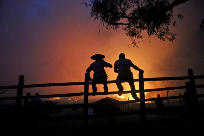 Residents watch the forest burn in Portezuelo, Chile, on Jan. 29, 2017. Chilean President Michelle Bachelet has announced that the country will continue with its various measures to deal with wild fires, one of the biggest natural disasters in the country for decades. (AP Photo/Esteban Felix)