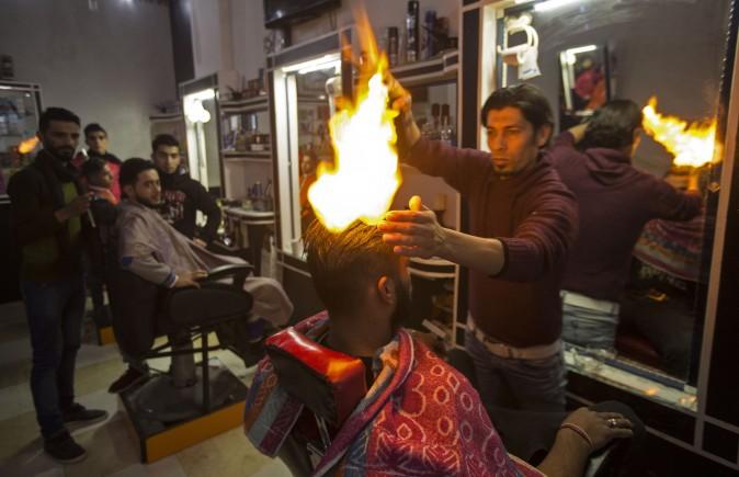 Ramadan Edwan, a Palestinian barber, uses fire in a hair-straightening technique with a client at his salon in the Rafah refugee camp, in the southern Gaza Strip on Feb. 1, 2017. (Mahmud Hams/AFP/Getty Images)