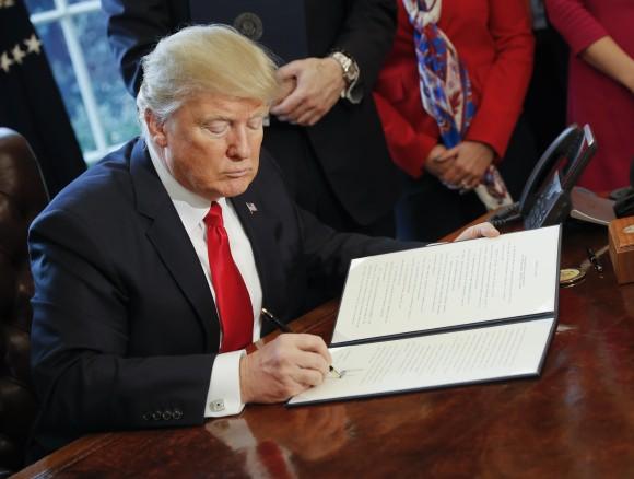 President Donald Trump signs an executive order in the Oval Office of the White House in Washington, Friday, Feb. 3, 2017. Trump signed an executive order that will direct the Treasury secretary to review the 2010 Dodd-Frank financial oversight law, which reshaped financial regulation after 2008-2009 crisis. (AP Photo/Pablo Martinez Monsivais)