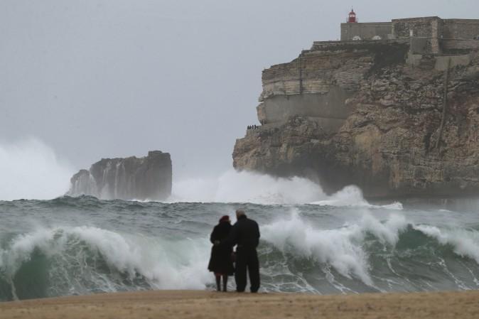 A couple watches the waves breaking in Nazare, Portugal, on Feb. 2, 2017. (AP Photo/Armando Franca)