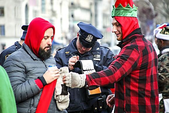 A police officer writes a ticket citing revellers for drinking alcohol in public during the annual Santacon in New York on Dec. 10, 2016. (KENA BETANCUR/AFP/Getty Images)