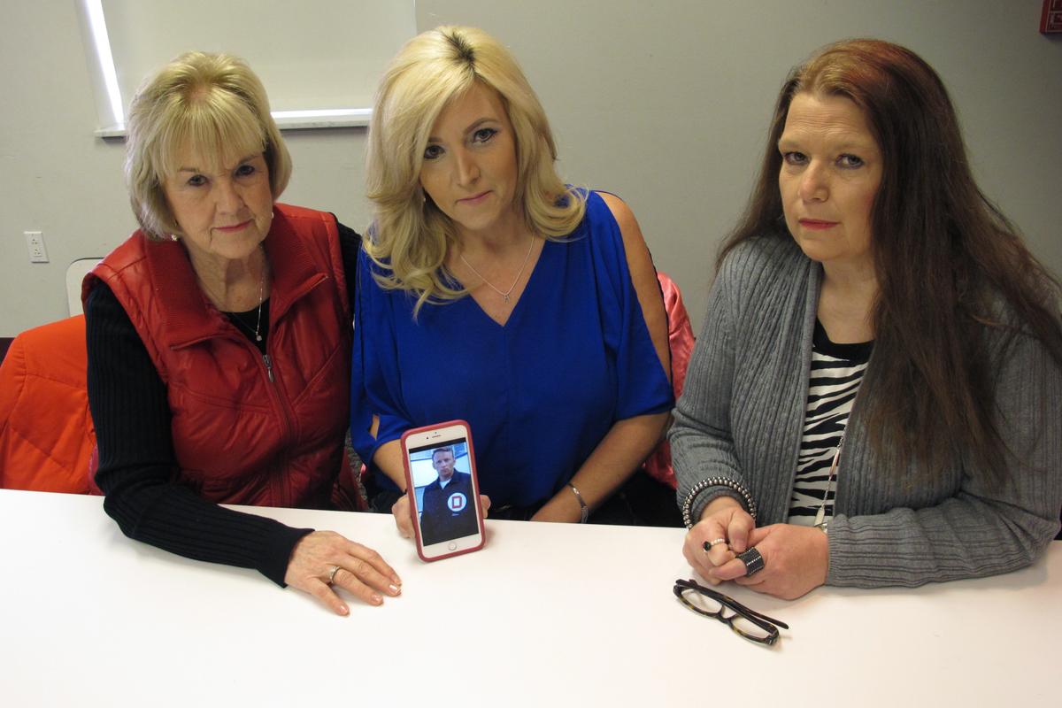 (L-R) Becky Cooper the ex-wife of former Columbus police Officer Niki "Nick" Cooper, and their daughters Amy Cooper and Lori Cooper display a photo of Niki Cooper from his days on the Columbus, Ohio, police force, in Columbus, OH., on Jan. 30, 2017. (AP Photo/Andrew Welsh-Huggins)