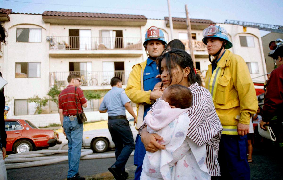 FILE - In this May 3, 1993, file photo, May Isabela Diego holds her infant son Pedro in the aftermath of a fire in an apartment complex in the Westlake section of Los Angeles. Diego had to drop her two children out of a window as fire threatened their safety. Police have arrested several people for the 1993 fire that killed 10 people, including seven children. (AP Photo/Michael Tweed, File)