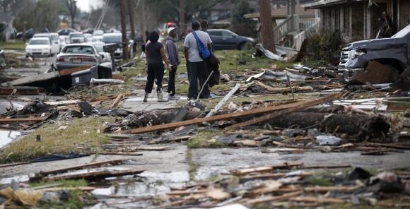 People walk amongst debris from destroyed homes after a tornado tore through the eastern neighborhood in New Orleans, Tuesday, Feb. 7, 2017. Gov. (AP Photo/Gerald Herbert)