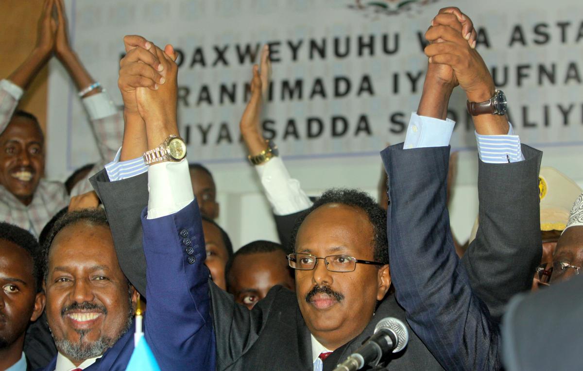 New Somali President Mohamed Abdullahi Farmajo (C) joins hands with incumbent President Hassan Sheikh Mohamud (L) as he celebrates winning the election and taking office in Mogadishu, Somalia on Feb. 8, 2017. (AP Photo/Farah Abdi Warsameh)