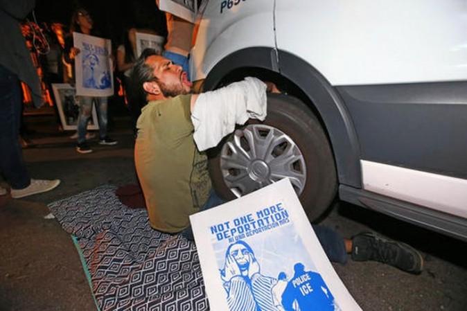 A protester locked himself to the van carrying Guadalupe Garcia de Rayos that is stopped by protesters outside the Immigration and Customs Enforcement facility, Wednesday, Feb. 8, 2017, in Phoenix.  (Rob Schumacher/The Arizona Republic via AP)