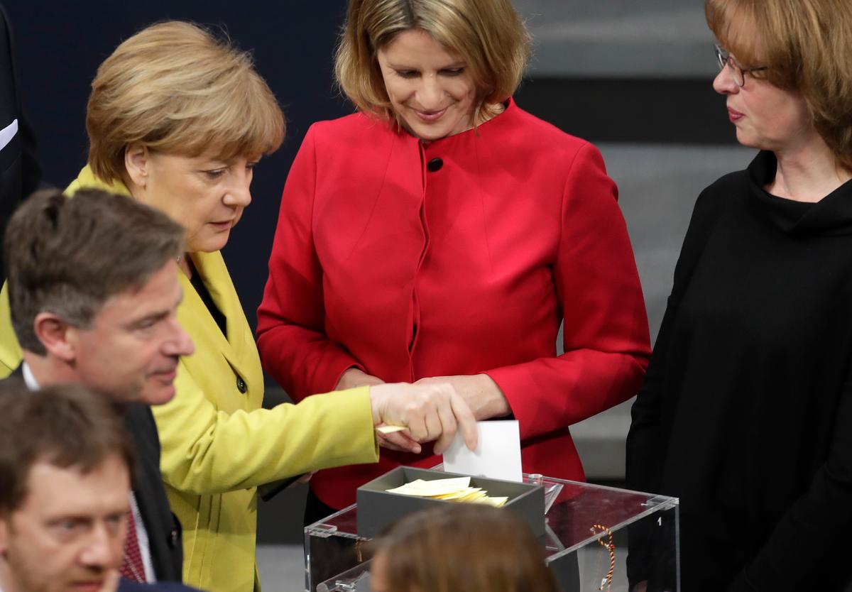 German Chancellor Angela Merkel (L) casts her ballot when a German parliamentary assembly came together to elect the country's new president in Berlin, Germany on Feb. 12, 2017. (AP Photo/Markus Schreiber)
