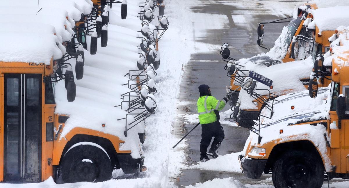 A worker clears snow off school buses, after schools were closed due to a storm, in Manchester, N.H., on Feb. 13, 2017. (AP Photo/Charles Krupa)