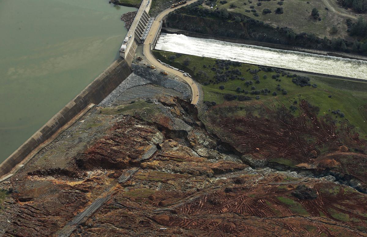 Erosion caused when overflow water cascaded down the emergency spillway is seen, bottom, as water continues to flow down the main spillway, top, of the Oroville Dam in Oroville, Calif., on Feb. 13, 2017. (AP Photo/Rich Pedroncelli)