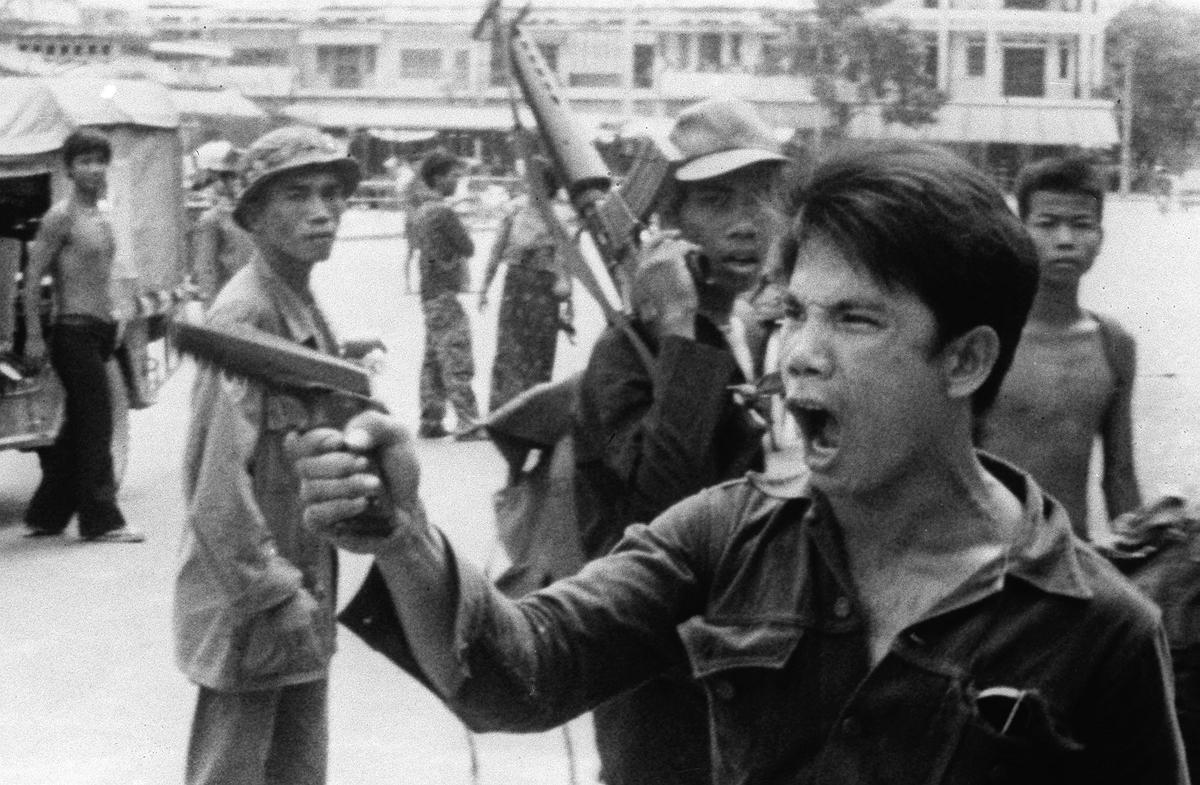A Khmer Rouge soldier waves his pistol and orders store owners to abandon their shops in Phnom Penh, Cambodia, on April 17, 1975, as the capital fell to the communist forces. A large portion of the city's population was forced to evacuate. (AP Photo/Christoph Froehder)