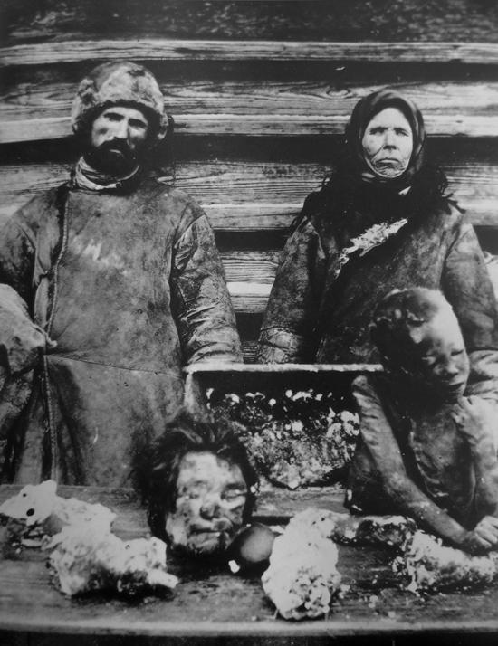 A man and woman with body parts of children in front of them, whom they had partially eaten. A famine in Russia between 1921 and 1922 is estimated to have killed 5 million to 10 million people. (Public Domain)
