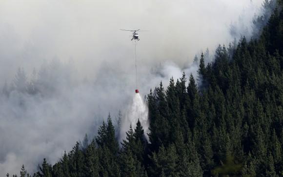 A helicopter dumps water on a wild fire in the Port Hills near Christchurch, New Zealand, Tuesday, Feb. 14, 2017. (AP Photo/Mark Baker)