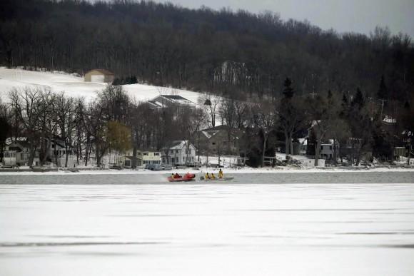 In this Feb. 13, 2017, photo, rescue crews search the frigid waters of Conesus Lake in Livonia, N.Y., for two missing snowmobilers who are believed to have fallen through the ice.  (Max Schulte/Democrat & Chronicle via AP)