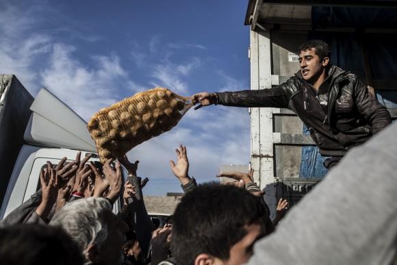 An Iraqi man distributes potatoes to civilians in the Samah district of Mosul, Iraq on Dec. 4, 2016. (AP Photo/Manu Brabo, File)