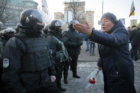 A woman holding a red carnation argues with riot police during a protest rally in front of the President Office in Kiev, Ukraine on Feb. 19, 2017. Protesters were demanding a stop to trade relations with Russia-occupied Ukrainian territories. (AP Photo/Efrem Lukatsky)