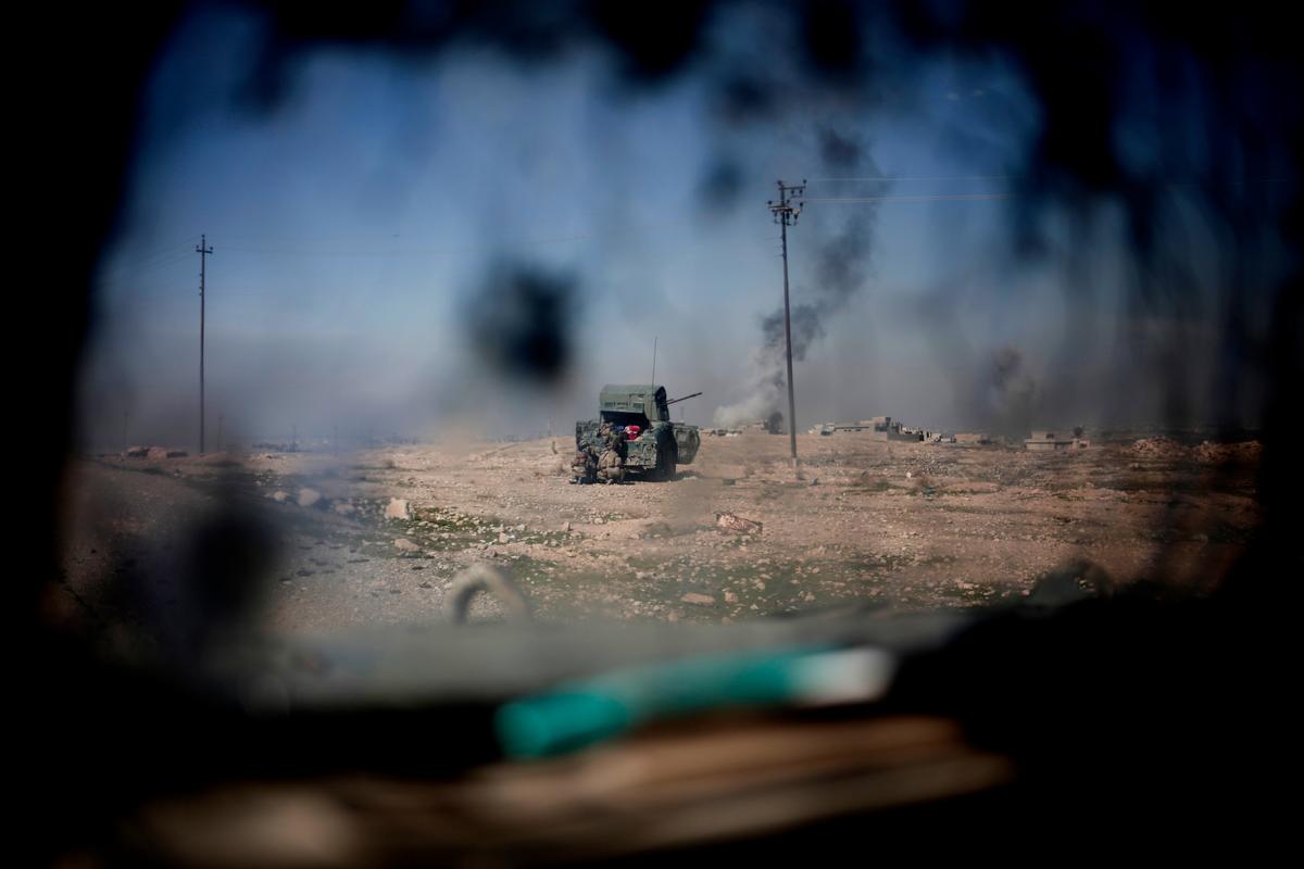 Iraqi police forces fire from a humvee at ISIS positions from a hillside outside the town of Abu Saif on Feb. 20, 2017. (AP Photo/Bram Janssen)