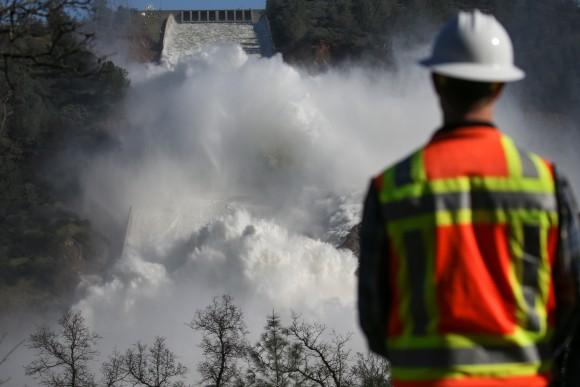 A worker keeps an eye on water coming down the damaged main spillway of the Oroville Dam in Oroville, Calif. on Feb. 14. (Elijah Nouvelage/Getty Images)