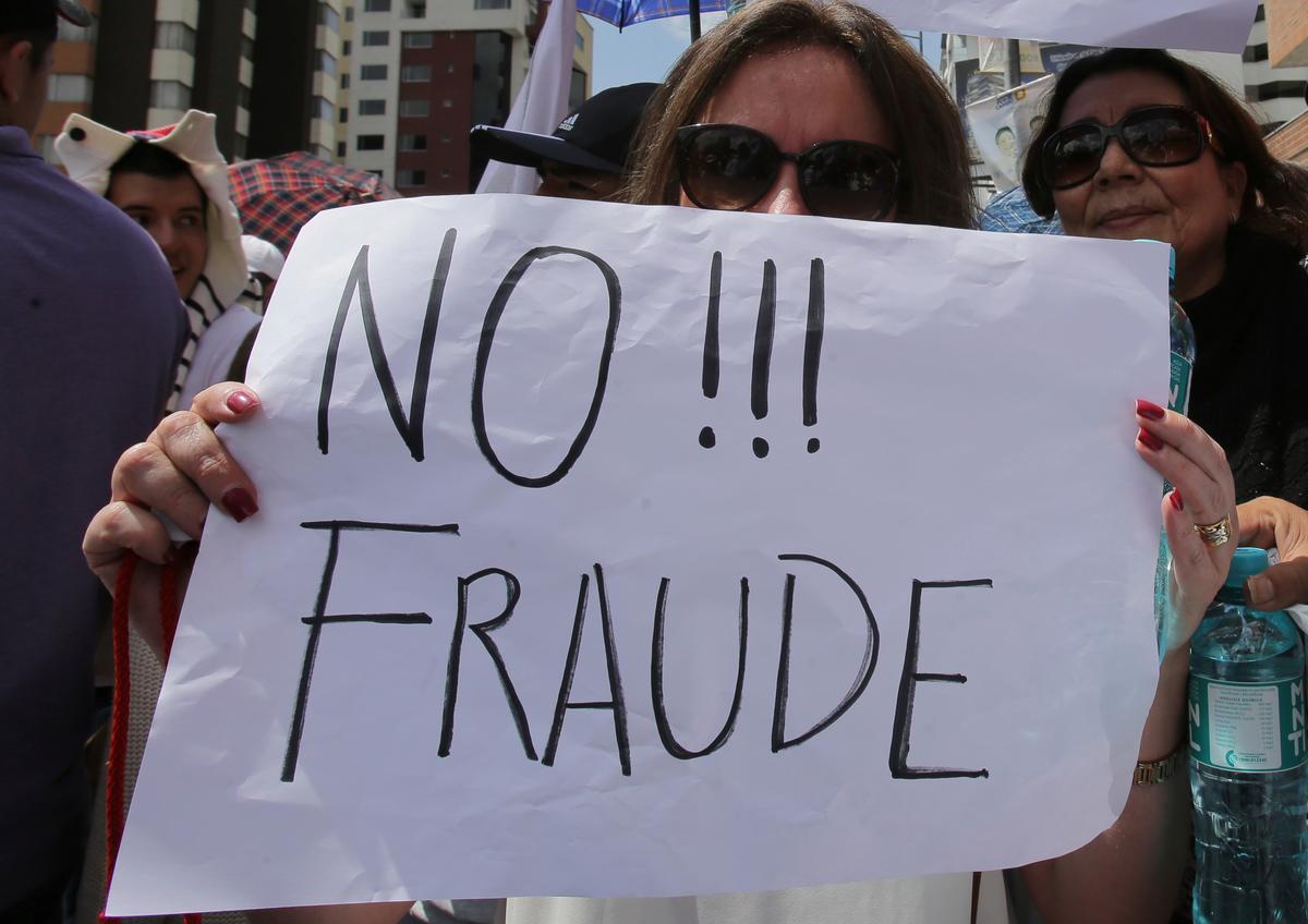 An opposition presidential candidate Guillermo Lasso's supporter holds a sign that read in Spanish "No to Fraud!" during protest outside Ecuador's National Electoral Council to demand the official results of the presidential elections, in Quito, Ecuador on Feb. 20, 2017. (AP Photo/Dolores Ochoa)