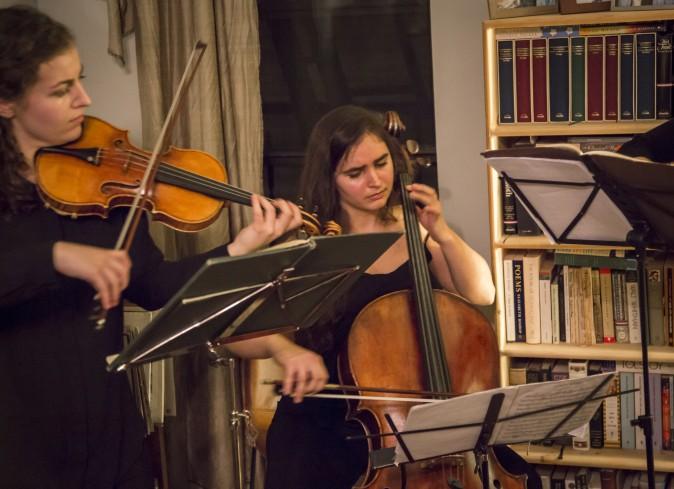 Clara Abel on cello perform (R) and Rannveig Marta Sarc on violin at a Groupmuse house concert in Harlem, New York, on Feb. 17, 2017. (Samira Bouaou/Epoch Times)