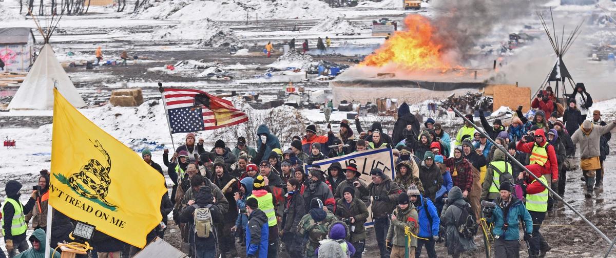 A fire set by protesters burns in the background as opponents of the Dakota Access pipeline leave their main protest camp near Cannon Ball, N.D., on Feb. 22, 2017. (Tom Stromme/The Bismarck Tribune via AP)